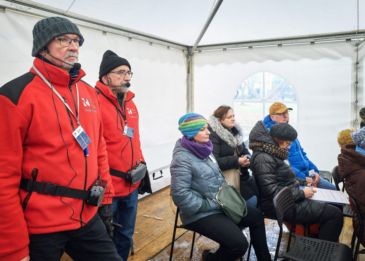 Uczestnicy i przewodnicy czekają w namiocie na rozpoczęcie wycieczki po terenie Przepompowni Staszic. 