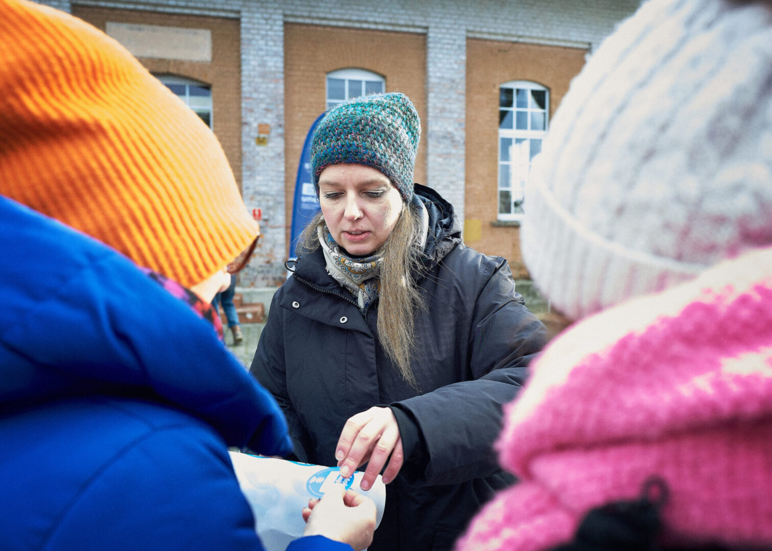 Pracownica instytucji kultury "Szyb Staszic w Tarnowskich Górach" rozdaje naklejki uczestnikom wycieczki. 