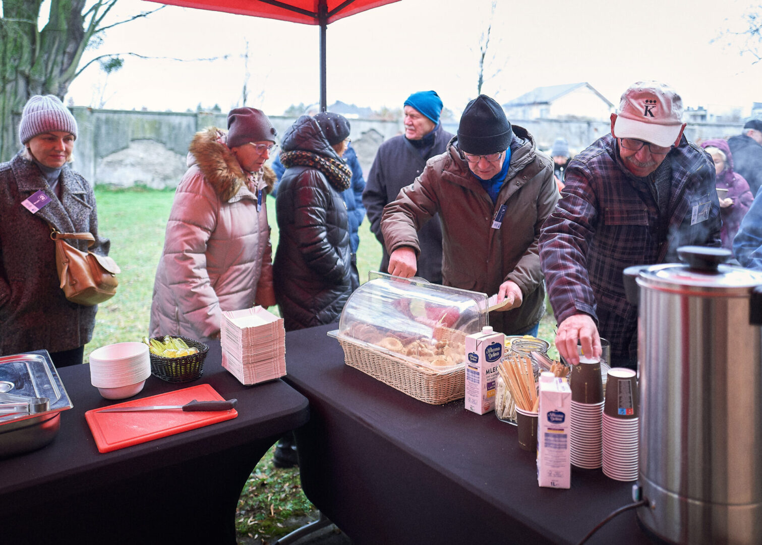 Uczestnicy wycieczki częstują się ciepłymi napojami i słodkimi przekąskami. 