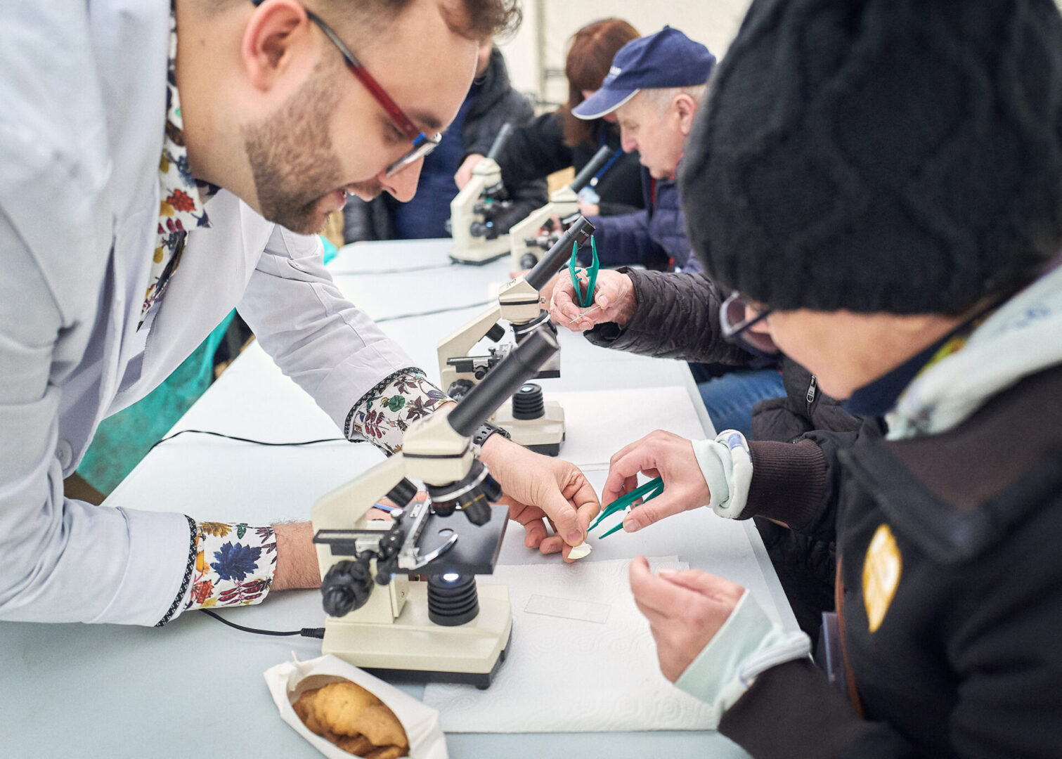 Lekarz pokazuje uczestniczce wycieczki wycinek pod mikroskopem. 