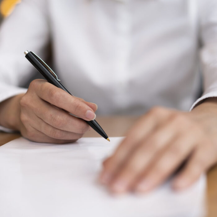 Dokumenty w podpisie, dłoń z długopisem nad dokumentami